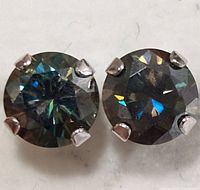 Close-up view of the two round moissanite stones in 10K gold prong settings showing reflective facets and glitter effects.