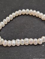 Close-up image showing the oval-shaped white fresh water pearls on a black background.