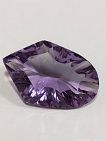 Close-up image of the faceted genuine amethyst gemstone showing its irregular fancy cut and purple color.