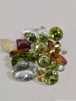 Various genuine loose gemstones in assorted shapes and colors arranged on white background