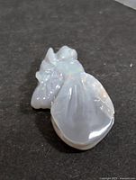 Carved opal gemstone showing front view of the carved piece with visible color play on a dark background.