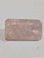 Close-up photo of a rectangular pale pink morganite gemstone with visible natural inclusions, showing its clarity and facets.