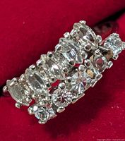 Close-up image of silver ring with clear stones on red background showing two rows of stones in various cuts.