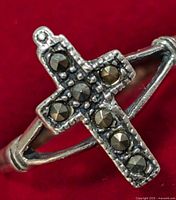 Close-up photo of sterling silver ring featuring marcasite stones arranged in a cross pattern on a red background.