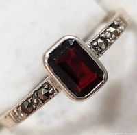 Close-up view of the sterling silver ring showing rectangular garnet stone and marcasite accents on the band.