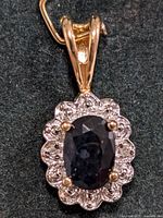 Close-up front view of the pendant showing the oval sapphire and surrounding cubic zirconia stones on a sterling silver setting.