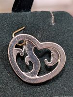 Close-up image of silver heart-shaped pendant showing front view of open scroll design inside.