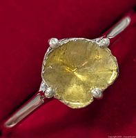 Close-up top view of the ring showing the yellowish translucent stone with internal markings and four silver prongs on a polished silver band.