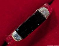 Angle view of silver ring with black onyx stone highlighting stone shape and band wear.