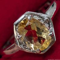 Close-up image of the sterling silver ring with a faceted oval citrine gemstone set in prongs on a silver band.