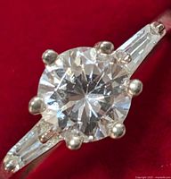 Close-up view of the round brilliant-cut clear cubic zirconia center stone in a prong setting with tapered baguette CZ accents on both sides of the band.