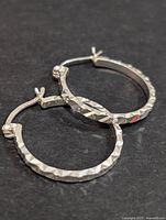 Top view of the two silver hoop earrings showing their round shape and textured faceted surface.