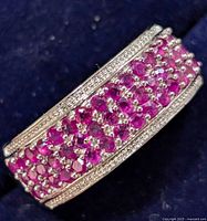 Close-up of the top of the silver ring showing rows of small round rubies set in the band.