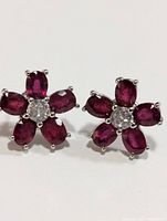 Pair of silver and ruby earrings showing front face with 5 ruby petals and central round clear stone