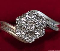 Close-up image of the top cluster diamond arrangement on the silver ring showing seven round-cut diamonds in a floral pattern.