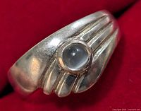 Close-up front and angled views of the silver gemstone ring showing the band design and gemstone set in bezel.