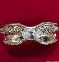 Front view of sterling silver ring with central cubic zirconia stone on red background.