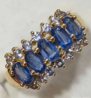 Close-up front view of tanzanite ring showing five oval tanzanite stones with clear round accents in gold-toned silver setting.