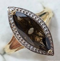 Close-up view of the top of the ring showing the marquise-cut smokey quartz surrounded by small clear stones in a silver setting with a yellowish hue.