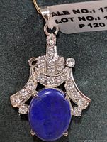 Close up front view of silver pendant with deep blue oval Lapis Lazuli stone and surrounding clear stones
