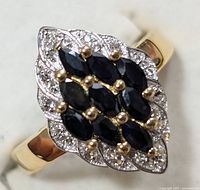 Close-up front view of ring showing marquise-shaped cluster with multiple marquise-cut blue sapphires and surrounding small clear stones.
