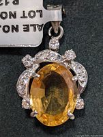 Front view of the sterling silver pendant featuring the oval citrine and surrounding cubic zirconia stones.
