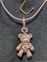 Close-up photo of sterling silver necklace with teddy bear pendant showing texture and details.