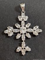 Front view of silver cross-shaped pendant adorned with clear cubic zirconia stones arranged in symmetrical pattern