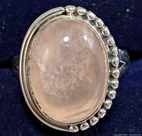 Close-up front view of the silver ring with oval rose quartz gemstone showing polished surface and detailed silver bead accents.