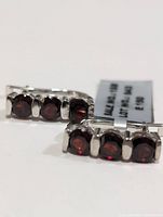 Photo of silver garnet earrings showing the front view with three round garnets each.