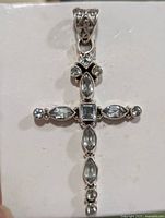 Front view of sterling silver cross pendant set with aquamarine stones on white background