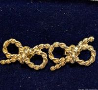 Pair of silver twisted rope design earrings shown on dark blue fabric background.