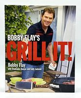 Front cover photo of the hardcover cookbook showing Bobby Flay and the title 'Bobby Flay's Grill It!' with grilling accessories