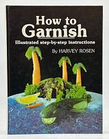 Front cover of the book showing garnishing example with fruit and vegetable carvings as palm trees, boat, and crocodile shapes.