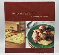 Front cover of the hardcover cookbook displaying the title and two food photos: fresh pasta and a prepared dish on a green plate.