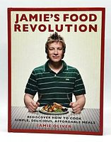 Front cover of Jamie Oliver's cookbook 'Jamie's Food Revolution' showing the author holding a plate of food.