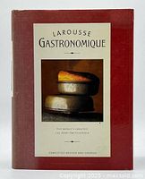 Front cover of Larousse Gastronomique showing the main title and an image of two stacked food molds with a baked dish on top.
