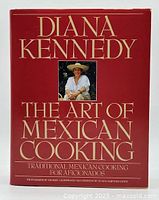 Front cover of The Art of Mexican Cooking by Diana Kennedy with photo of author and gold text on a red background.