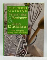 Front cover of the cookbook featuring title and authors' names along with kitchen utensils in the background.