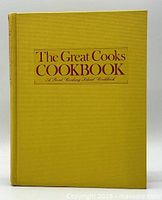 Front cover of The Great Cooks Cookbook showing title text on yellow textured cover.