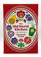 Front cover view of the hardcover cookbook 'The Old World Kitchen' showing colorful folk art design with fruits and flowers on a red background.