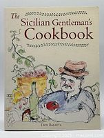Front cover of The Sicilian Gentleman's Cookbook showing illustrated man with a hat, grapes, bottle, and tomato on cream background with title and author name.