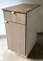 Three-quarter view of cabinet showing granite top, drawer and door fronts