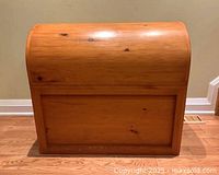 Front view of closed chest showing curved lid and knotty wood finish