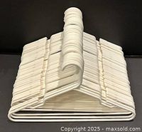 Stack of approximately 50 white plastic hangers