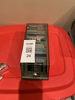 Closed plastic storage case containing floppy disks inside, resting on a red surface.