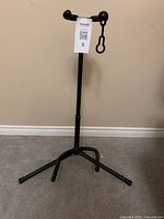Photo showing the full view of the black metal guitar stand with foldable legs and adjustable height pole.