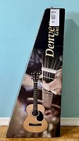 Denver branded cardboard box with an image of an acoustic guitar being played, showing branding and product packaging.