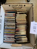 CD collection in large box showing stacked jewel cases and visible spines representing 50-60 discs.