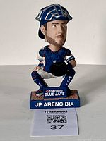 Front view of JP Arencibia bobblehead with detailed view of the face, uniform, mitt, and base showing name and team logo.